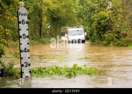 La voie de campagne est inondée, avec un indicateur de niveau d'eau et un véhicule en panne qui n'est pas mis au point à l'arrière-plan. Beaucoup Hadham, Hertfordshire. ROYAUME-UNI Banque D'Images