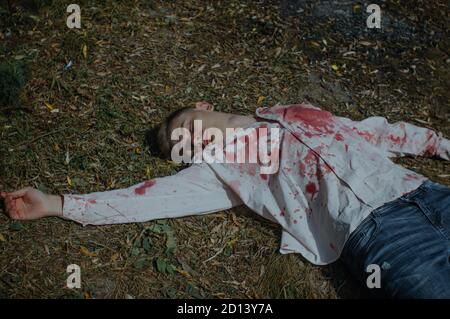 Le jeune homme mort est couché sur le sol dans un chemise sanglante Banque D'Images