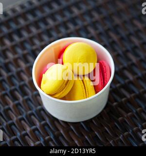 Macarons multicolores dans une boîte ronde blanche sur un osier tableau Banque D'Images