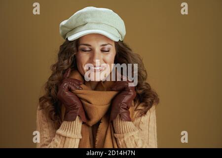 Bonjour octobre. Bonne femme tendance d'âge moyen dans un foulard avec des gants en cuir sur fond marron. Banque D'Images