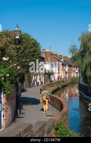 Une femme voyage en Angleterre, vue arrière en été d'une femme mûre marchant le long d'une rue pittoresque dans le Wiltshire, Angleterre, Royaume-Uni. Banque D'Images