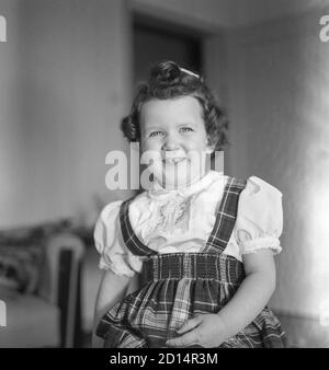 Vintage années 1950 style de vie , deux ans Old Girl pose pour caméra dans son pull à carreaux, États-Unis Banque D'Images