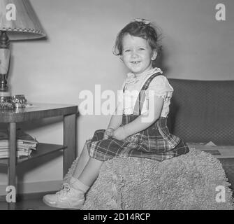 Vintage années 1950 style de vie, deux ans Old Girl pose pour caméra dans son pull à carreaux, États-Unis Banque D'Images