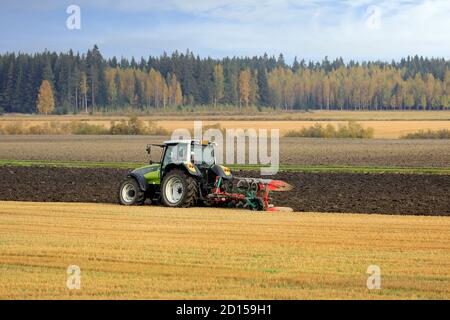 Les agriculteurs cultivent le champ avec un tracteur vert Valtra et labourent le matin ensoleillé de l'automne dans le sud de la Finlande. Jokioinen, Finlande. 2 octobre 2020 Banque D'Images
