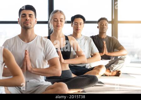 Exercice de méditation. Jeunes sportifs pratiquant le yoga pendant la leçon de groupe en Studio Banque D'Images