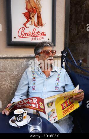 Italie, Sicile, Taormina, vieil homme élégant avec des lunettes de soleil de conception rouge lisant sa journal sur la terrasse d'une caf? dans corso umberto Banque D'Images