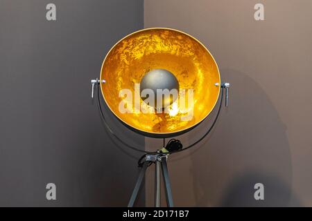 Lampe à réflecteur dorée sur le trépied dans le coin Banque D'Images