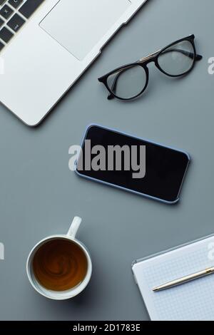 Au-dessus de la vue, posez un ordinateur portable et un smartphone sur un arrière-plan de travail gris avec une tasse à café et un espace de copie Banque D'Images