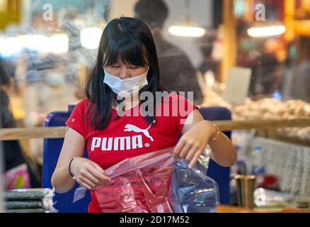 Une femme de vente dans un centre commercial portant un masque de protection. Banque D'Images