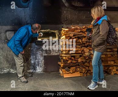 Atelier traditionnel de pain en seigle du Valais à Goppenstein-Erschmatt, Suisse. L'ancien four en pierre du centre communautaire d'Erschmatt n'est chauffé qu'une fois par an. Avant l'entrée des pains dans le four, les cendres et les émonteurs sont enlevés. La chaleur des pierres est suffisante pour cuire tous les pains de seigle Banque D'Images