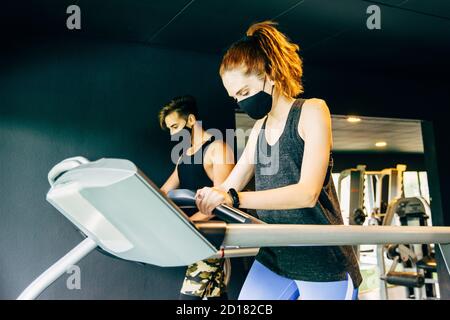 une jeune femme et un jeune homme portant un visage masque exercice à la salle de gym Banque D'Images
