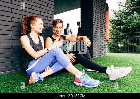 une jeune femme parle à un jeune homme et montre son smartphone après avoir fait de l'exercice à la salle de gym Banque D'Images