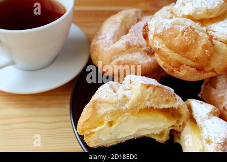 Délicieux feuilletés à la crème française servis sur une table en bois avec un Tasse de thé chaud Banque D'Images