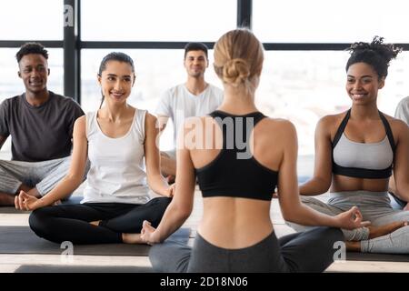 Groupe multiculturel d'homme et de femme pratiquant le yoga avec instructeur en studio Banque D'Images