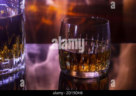 Carafe et verre avec un fond de whisky sur Fiery. Carafe et verre sont mis en miroir sur une table en verre. Banque D'Images