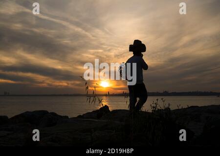 Silhouette d'un pédalier au coucher du soleil à Istanbul. Il vend des chapeaux de paille et des fleurs. Banque D'Images