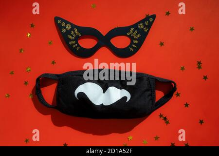Mascarade festive et masque hygiénique fantaisie, décoration de Noël et du nouvel an 2021 sur fond rouge. Auto-isolement des fêtes et pandémie du coronavirus Banque D'Images