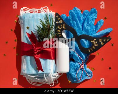 Masques hygiéniques gel antibactérien et gants médicaux en cadeau avec ruban rouge, décoration de Noël et du nouvel an 2021 sur fond rouge. Vacances Banque D'Images
