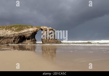 Trou dans la formation rocheuse à la plage des cathédrales, Ribadeo, Lugo, Galice, Espagne. Playa de las Catedrales. Arche en pierre. Banque D'Images