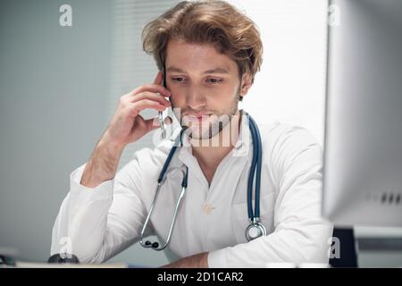 Un médecin dans son bureau effectuant des appels importants. Banque D'Images