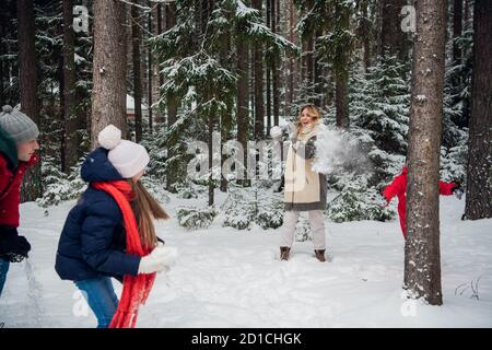 Maman, papa, fils et fille ont décidé de jouer des boules de neige entre les arbres dans la neige. Banque D'Images