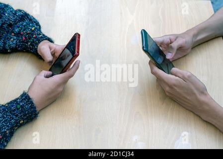 Deux personnes face à face tiennent un smartphone sur un tableau Banque D'Images