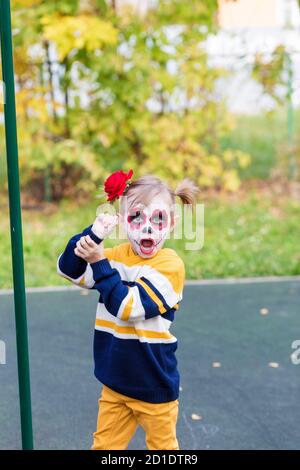 Une petite fille au visage peint, regardant l'appareil photo le jour des morts. Banque D'Images