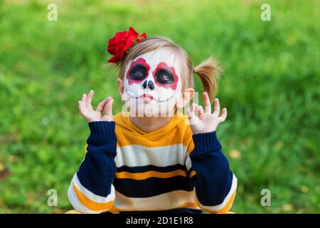 Une petite fille au visage peint, regardant un appareil-photo le jour mexicain des morts. Banque D'Images