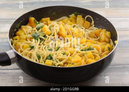 Pétoncles avec kale et courge butternut, plat de pâtes de légumes avec verser la sauce à la crème dans une poêle Banque D'Images