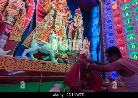 Howrah, Bengale occidental, Inde - 5 octobre 2019 : prêtres hindous couvrant les saints pots avec du gaamcha rouge, serviette, comme rituel pour le culte de la déesse Durga, Sho Banque D'Images