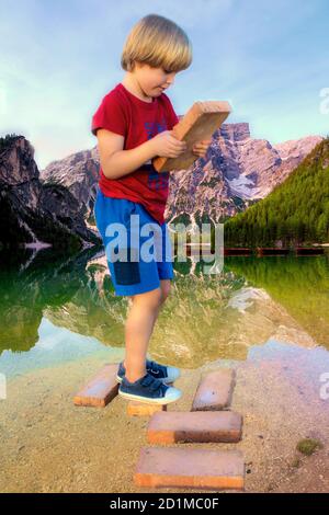 Enfant sur des briques dans le lac et les montagnes paysage. Banque D'Images