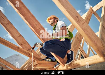 Constructeur compétent assis en hauteur sur le faisceau Banque D'Images