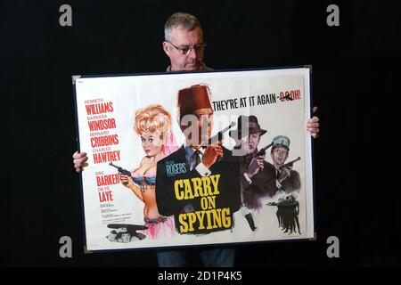 Un employé de Prop Store détient une affiche britannique pour le film « Carry on Spying » de 1964 (environ 1 à 2 000 £) lors d'un avant-goût de la prochaine vente aux enchères d'affiches de cinéma par le Prop Store de Chorleywood, Hertfordshire. Banque D'Images