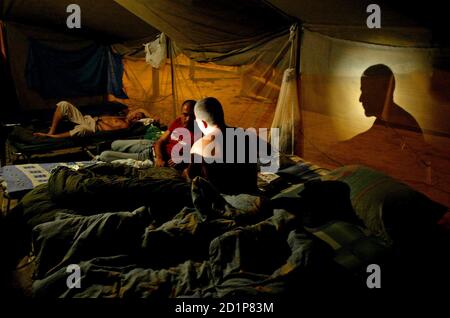 Des agents de police des frontières israéliens s'assoient la nuit dans une tente située dans la base militaire Reim du sud d'Israël, construite pour abriter des milliers de soldats qui prendront part à l'évacuation des colonies juives de la bande de Gaza, le 10 août 2005. À compter du 17 août, quelque 55,000 soldats et policiers retirera quelque 9,000 colons juifs dans 21 colonies de la bande de Gaza et quatre en Cisjordanie. Photo prise le 10 août 2005. REUTERS/Sebastian Scheiner/Pool SHP/VP