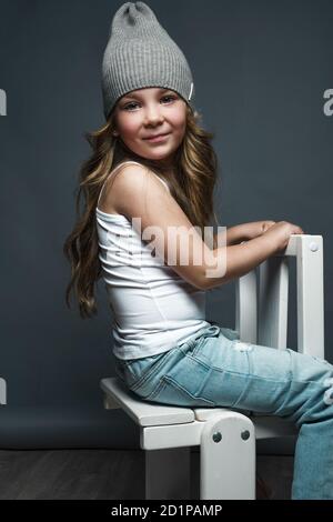 Petite fille modèle professionnellement posant dans le studio en jeans et un T-shirt blanc. Tests de modèles Banque D'Images