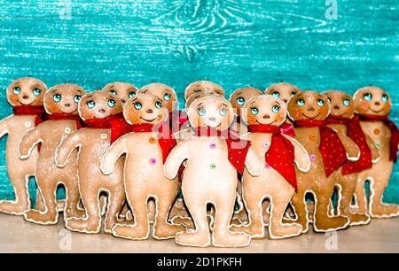 Beaucoup d'hommes de pain d'épice dans les foulards rouges sur un fond gris-bleu . Décoration de Noël pour la maison. Jouet de Noël. Banque D'Images