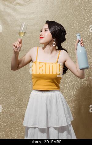 Portrait d'une jolie fille souriante dans les mains bouteille de champagne et de lunettes de vin avec champagne. Banque D'Images