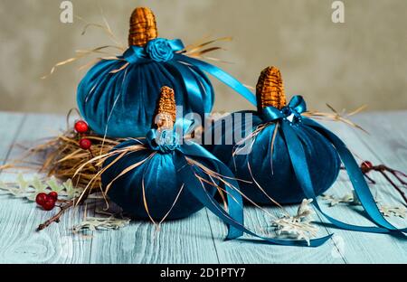 De belles citrouilles bleues en velours sont décorées de divers éléments et rubans . Décoration pour les fêtes d'Halloween. Décoration de Noël Banque D'Images