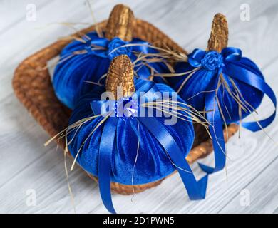 De belles citrouilles bleues en velours sont décorées de divers éléments et rubans dans un petit panier en osier. Décoration pour Halloween Banque D'Images