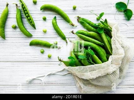 Sac écologique réutilisable rempli de pois frais sur fond blanc arrière-plan en bois Banque D'Images