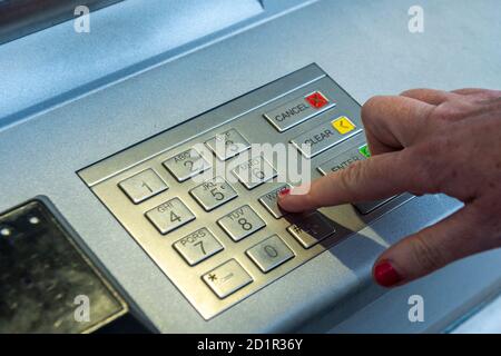 Femme entrant son NIP dans un guichet automatique ou un distributeur de billets pour retirer de l'argent en Irlande. Banque D'Images