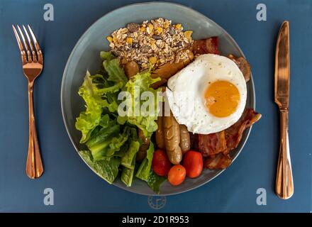 Petit-déjeuner continental avec œufs frits, saucisses frites, légumes sur plaque blanche. Foyer sélectif. Banque D'Images