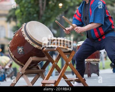 Homme jouant des tambours de la tradition musicale japonaise lors d'un événement public en plein air. Banque D'Images