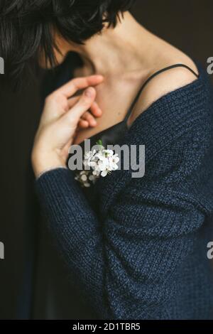 Femme dans un gilet tricoté main avec une branche blossiming dans sa main. Portrait sans visage. Banque D'Images