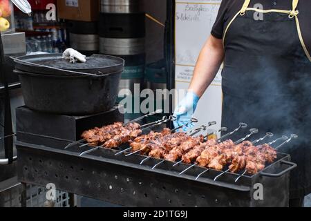 Gros plan de brochette de viande, grillée au barbecue, shashlik ou shashlyk de porc pour un pique-nique, homme se préparant et rôtir dans un marché de rue, prêt à manger Banque D'Images