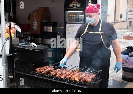Gros plan de brochette de viande, grillée au barbecue, shashlik ou shashlyk de porc pour un pique-nique, homme portant un masque de préparation et de rôtir dans un marché de rue Banque D'Images