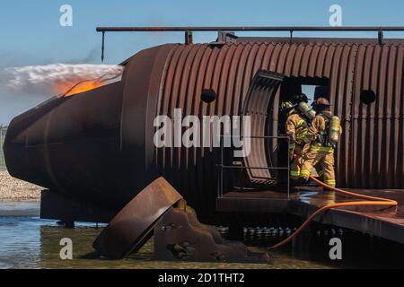 Les pompiers du 436e Escadron de génie civil et du 177e Escadron de génie civil éteignent des flammes à l'intérieur d'un entraîneur d'incendie d'avion à la structure d'entraînement d'incendie en direct de l'avion, le 22 septembre 2020, à la base aérienne de Douvres (Delaware). Les séances de formation sur les incendies en direct par avion sont utilisées pour actualiser les compétences et satisfaire aux autres exigences annuelles de formation que les pompiers doivent suivre. (É.-U. Photo de la Force aérienne par Airman Brandan Hollis) Banque D'Images