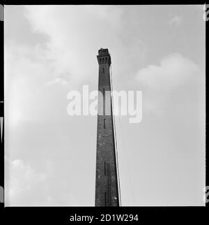 La cheminée de Salt's Mill, avec deux steeplejacks qui viennent d'être visibles au sommet, Saltair, Shipley, Bradford, West Yorkshire, Royaume-Uni. Banque D'Images