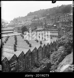 Vue vers le nord sur le pont Hebden avec les toits éclairés au nord de Hebden Works en premier plan et les terrasses sur Lee Mill Road au loin, West Yorkshire, Royaume-Uni. Banque D'Images