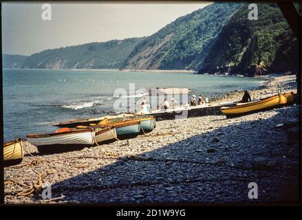 Port de Clovelly, Clovelly, Torridge, Devon. Une vue du sud-est de l'autre côté de l'estran de Clovelly Harbour, avec de petits bateaux enchés sur le bardeau et des personnes assises et debout sur la cale et la plage au-delà. Banque D'Images